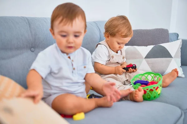스러운 아기들 소파에 앉아서 집에서 장난감을 가지고 — 스톡 사진