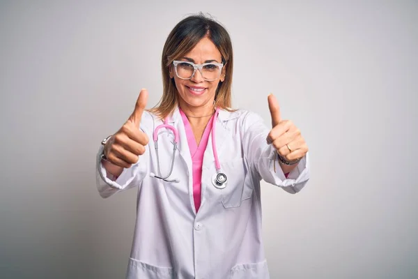 분홍빛 청진기를 아름다운 중년의 의사는 손으로 긍정적 행동을 승인한다 승자의 — 스톡 사진