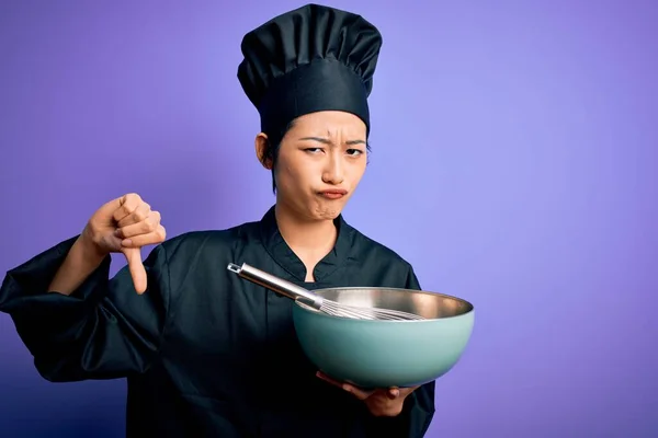 年轻美丽的中国厨师 身穿炊事服 头戴大头帽 满脸怒容 负面迹象显示不喜欢大拇指朝下 拒绝的观念 — 图库照片