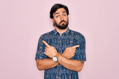 Pembe arka planda hippi tarzı giyinmiş genç, Latin asıllı bohem bir adam. Her iki tarafı da işaret ediyor. Farklı yönlerden.