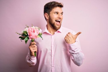 Sarışın, sakallı, mavi gözlü, elinde güzel bir buket çiçek tutan ve gülümseyen bir gülümsemeyle baş parmağıyla yüzünü gösteren genç bir romantik adam.