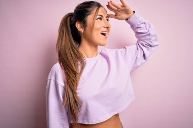 Pembe izole edilmiş arka plan üzerine kazak giyen genç ve güzel bir bayan çok mutlu ve tebessüm ediyor. Konsept aranıyor.