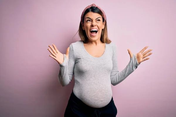 若い美しいブルネットの女性は 孤立したピンクの背景に赤ん坊を期待して狂気と怒鳴り声を上げ 積極的な表現と腕を上げて叫びました 欲求不満の概念 — ストック写真