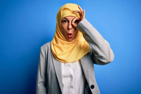 中年黑发女商人头戴穆斯林传统的头巾 头戴蓝色背景的头巾 做着令人惊讶的手势 用手指看了看 难以置信的表情 — 图库照片
