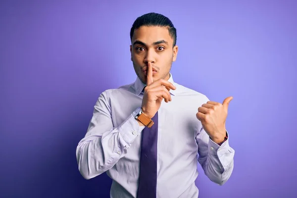 孤立した紫色の背景の上に立ってエレガントなネクタイを身に着けている若いブラジルのビジネスマンは 唇の側に手を指して上の指で静かにするように求めている 沈黙と秘密の概念 — ストック写真