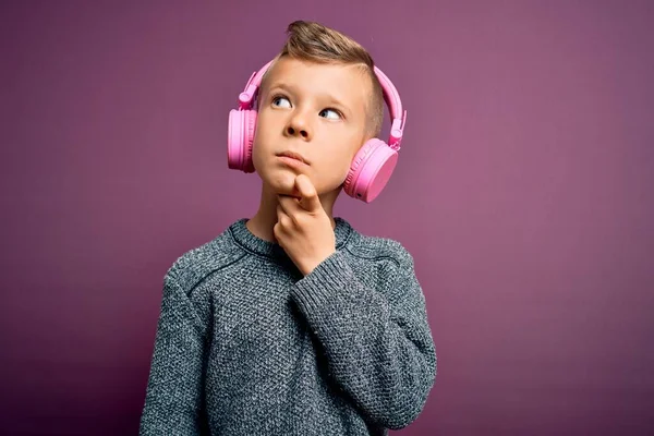 Mladý Běloch Sluchátkách Poslouchá Hudbu Purpurovém Pozadí Rukou Bradě Přemýšlí — Stock fotografie