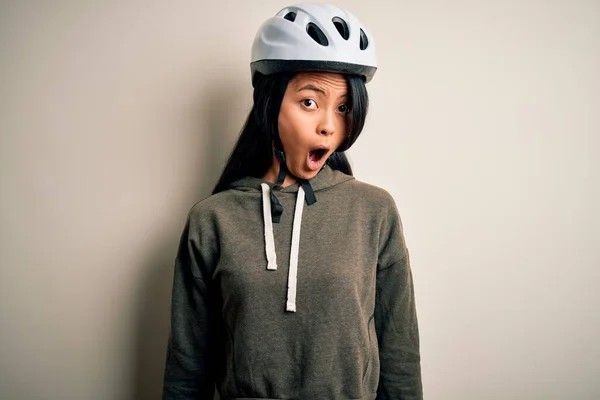若いです美しい中国人女性身に着けています自転車ヘルメット上の隔離された白い背景恐怖と驚きの表情でショックを受けました 恐怖と興奮した顔 — ストック写真