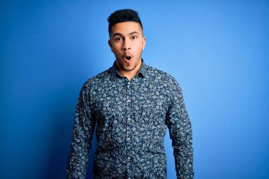 Genç ve yakışıklı bir adam yalnız mavi arka planda dikilirken korku, korku ve heyecan dolu bir yüz ifadesi karşısında dehşete düşmüş ve şok olmuştu..