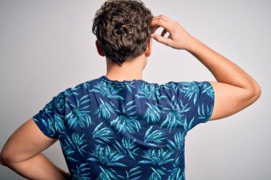 Sarışın, yakışıklı, tatilde. Kıvırcık saçlı, sıradan bir yaz tişörtü giyiyor. Geriye doğru, elleri kafasında şüpheyi düşünüyor.