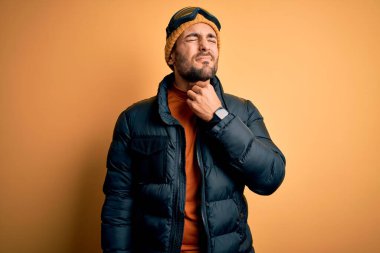 Sakallı, kar maskesi takan, kar maskesi takan, boynu ağrıyan, boğazı ağrıyan, grip ve enfeksiyon kapmış yakışıklı bir kayakçı.