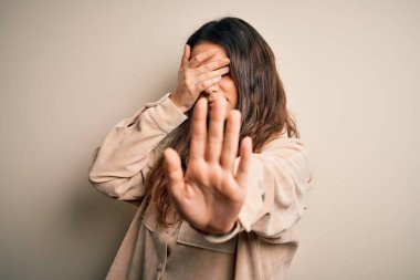 Genç, güzel, esmer bir kadın, beyaz arka planda dikiliyor, gözleri ellerle örtüyor ve üzgün ve korku dolu ifadelerle jest yapıyor. Utanç verici ve olumsuz bir kavram..