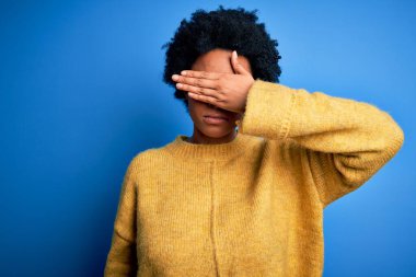Kıvırcık saçlı, sarı kazak giyen, gözleri elle kaplı, ciddi ve üzgün görünen güzel Afro-Amerikan kadın. Görme, saklama ve reddetme konsepti