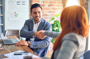 Mutlu ve kendinden emin gülümseyen genç ve güzel iş adamları. Ofiste anlaşmak için gülümseyerek tokalaşmak.