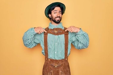 Almanya Festivali için geleneksel Alman Ekim Festivali kıyafeti giyen yakışıklı genç adam yüzünde bir tebessümle kendinden emin, kendini gururlu ve mutlu bir şekilde gösteriyor..