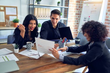 Group of business workers smiling happy and confident. Working together with smile on face reading documents and  speaking at the office