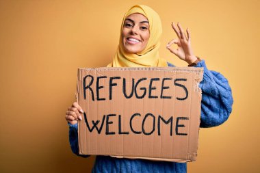 İslami tesettüre bürünmüş güzel bir Arap kadın elinde mültecilerle bayrak tutuyor. Mesajı hoş karşılıyor.