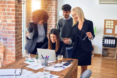 Bir grup iş adamı mutlu ve kendinden emin gülümsüyor. Ofiste dizüstü bilgisayarla gülümseyerek birlikte çalışıyoruz.