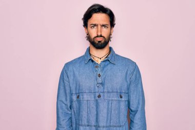 Pembe arka planda hippi tarzı giyinen genç, yakışıklı bohem adam depresif ve sıkıntılı, sinirli ve korkmuş. Üzücü ifade.