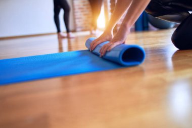 Spor salonunda yoga yapmak için spor minderi kullanan genç ve güzel bir sporcu.