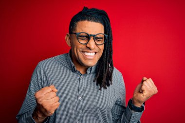 Rastgele gömlek ve gözlük takmış, başarılı olmak için heyecanlanan kolları havada ve gözleri kapalı zaferi kutlayan Afro-Amerikan genç adam. Kazanan konsept.