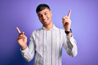 Zarif bir iş gömleği giyen, mor arka planda duran, kendine güvenen, farklı yönleri gösteren genç, yakışıklı İspanyol bir adam. Reklam için boşluk kopyala