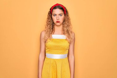 Sarı arka planda dikilirken mavi gözlü güzel sarışın kadın depresyonda ve endişeli, sinirli ve korkmuş. Üzücü ifade.