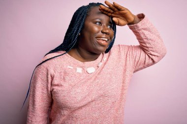Afro-amerikan kadın örgü örüyor pembe arka planda rahat bir süveter giyiyor çok mutlu ve gülümsüyor başlarını kaldırıp uzaklara bakıyor. Konsept aranıyor.
