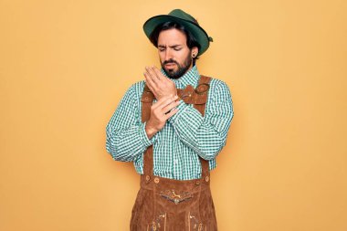 Almanya festivali için geleneksel Alman Ekim Festivali kıyafeti giyen yakışıklı bir adam. Ellerinde ve parmaklarında ağrı, eklem iltihabı.