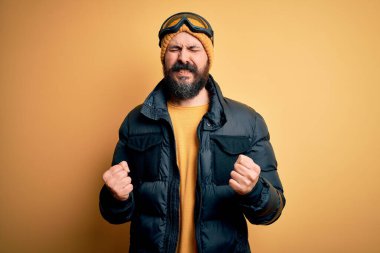 Sakallı, kar bezi giymiş, kar maskesi takmış, kar gözlüklü yakışıklı kayakçı. Kolları havada ve gözleri kapalı zaferi kutlarken gülümsüyor. Kazanan konsept.