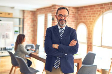 Orta yaşlı işadamı mutlu ve kendinden emin gülümsüyor. Yüzünde gülümsemeyle ofisteki iş kadınıyla çalışmak.