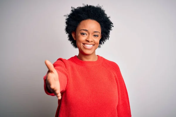 赤のカジュアルなセーターを着て巻き毛を持つ若い美しいアフリカ系アメリカ人アフロ女性は 挨拶や歓迎として握手を提供フレンドリーな笑みを浮かべて 成功事業 — ストック写真