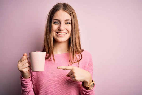 Fiatal Gyönyörű Vörös Hajú Iszik Bögre Kávé Felett Elszigetelt Rózsaszín — Stock Fotó