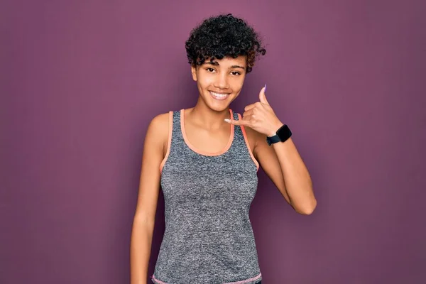 年轻美丽的非洲裔美国女运动员穿着运动服做运动时 笑着用手和手指做电话手势 就像在电话里说话一样 交流概念 — 图库照片