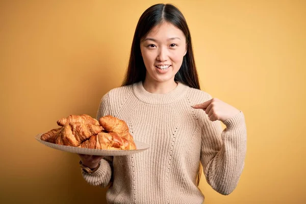 Joven Asiática Mujer Sosteniendo Francés Pastelería Croissant Sobre Amarillo Aislado — Foto de Stock