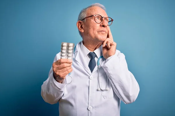 Starší Šedovlasý Lékař Drží Farmaceutické Pilulky Nad Modrým Pozadím Vážná — Stock fotografie