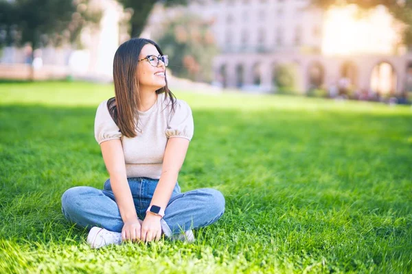 若い美しい女性が幸せと自信を笑顔 公園で笑顔で草の上に座って — ストック写真