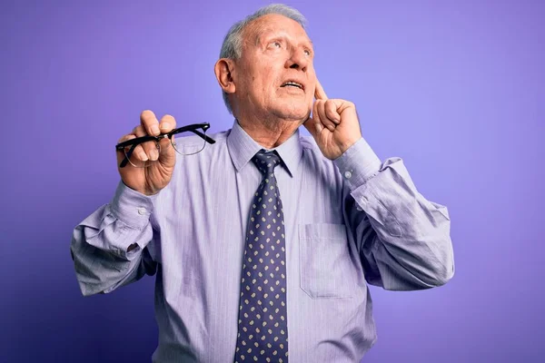 Senior Hombre Pelo Gris Sosteniendo Gafas Corrección Sobre Fondo Púrpura —  Fotos de Stock