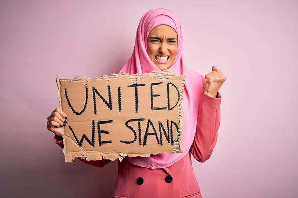 ピンクのイスラム教徒のヒジャーブを身に着けている若い活動家の女性が団結してバナーを持っている私たちは怒りでイライラし 失望叫び 狂気と大声で手を上げ 怒りの概念 — ストック写真