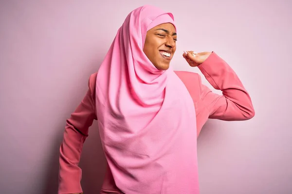 年轻的非洲裔美国女人 头戴穆斯林头巾 头戴穆斯林头巾 背景是孤立的粉色 背向后伸展 疲倦而放松 困倦而又打呵欠 直到清早 — 图库照片