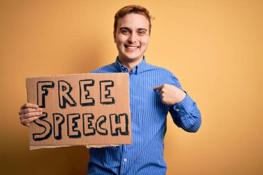 Genç, yakışıklı, kızıl saçlı, özgürlük isteyen özgür konuşma mesajıyla bayrak tutan mutlu ve gururlu bir kişiyi işaret eden bir adam.