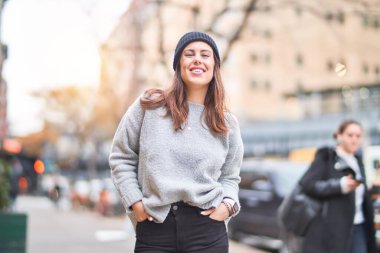 Mutlu ve kendinden emin gülümseyen genç ve güzel bir kadın. Yüzünde gülümsemeyle kentte yürürken