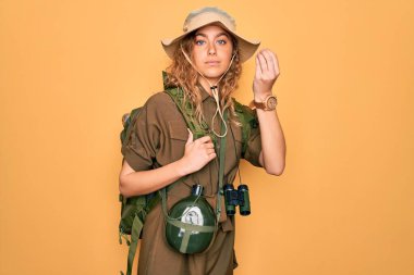 Mavi gözlü genç sarışın kaşif sırt çantası ve su kantiniyle yürüyüş yapıyor. İtalyan jestleri yapıyor. Elleri ve parmakları kendine güveni tam.