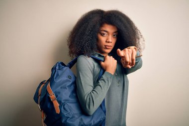 Afro saçlı, sırt çantalı, kamerayı işaret eden Afro Amerikalı genç bir bayan öğrenci. Ve sen, el işareti, ön taraftan pozitif ve kendinden emin bir jest.