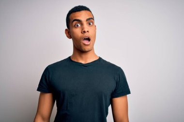 Genç, yakışıklı, Afro-Amerikalı bir adam beyaz arka planda duran, kuşkucu, alaycı ve ağzı açık bir şekilde şaşırmış beyaz tişört giyiyor.