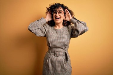 Güzel bir Arap iş kadını. Elbise ve gözlük takıyor. Sarı arka planda duruyor. Şaşırdım ve çıktım.