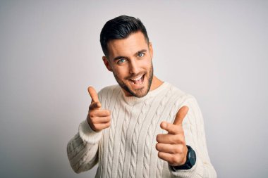 İzole edilmiş beyaz arka plan üzerinde dikilmiş, neşeli ve komik yüzlü genç ve yakışıklı bir adam. İyi enerji ve titreşimler.