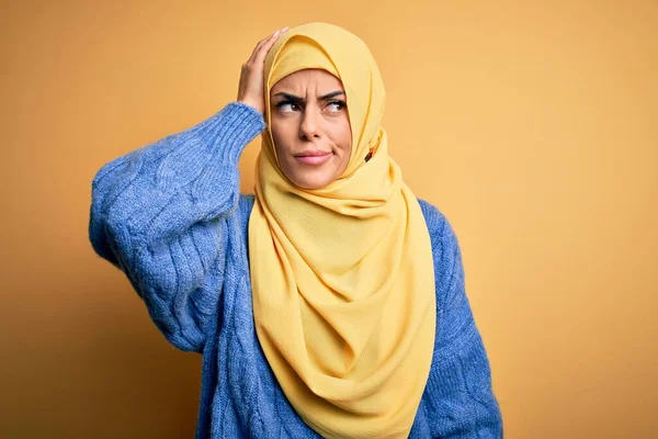 年轻美丽的黑发穆斯林女子 头戴阿拉伯头巾 头戴黄褐色的背景 迷惑和疑惑的问题 拿不定主意 手拿着头思考 沉思的概念 — 图库照片