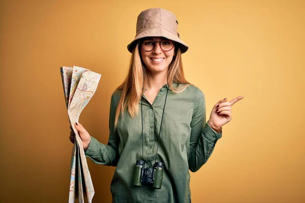 Blonde 탐험가인 모자를 쌍안경을 휴가중에 지도를 손가락으로 행복하게 가르키는 쌍안경을 — 스톡 사진