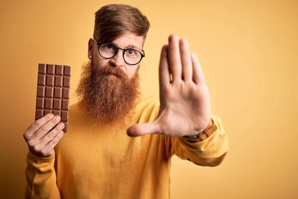 Ιρλανδός Κοκκινομάλλης Γενειάδα Τρώει Μια Γλυκιά Σοκολάτα Πάνω Από Κίτρινο — Φωτογραφία Αρχείου