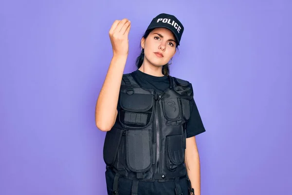 身穿紫色背景防弹背心制服的年轻女警察手指手画脚地做意大利手势 — 图库照片